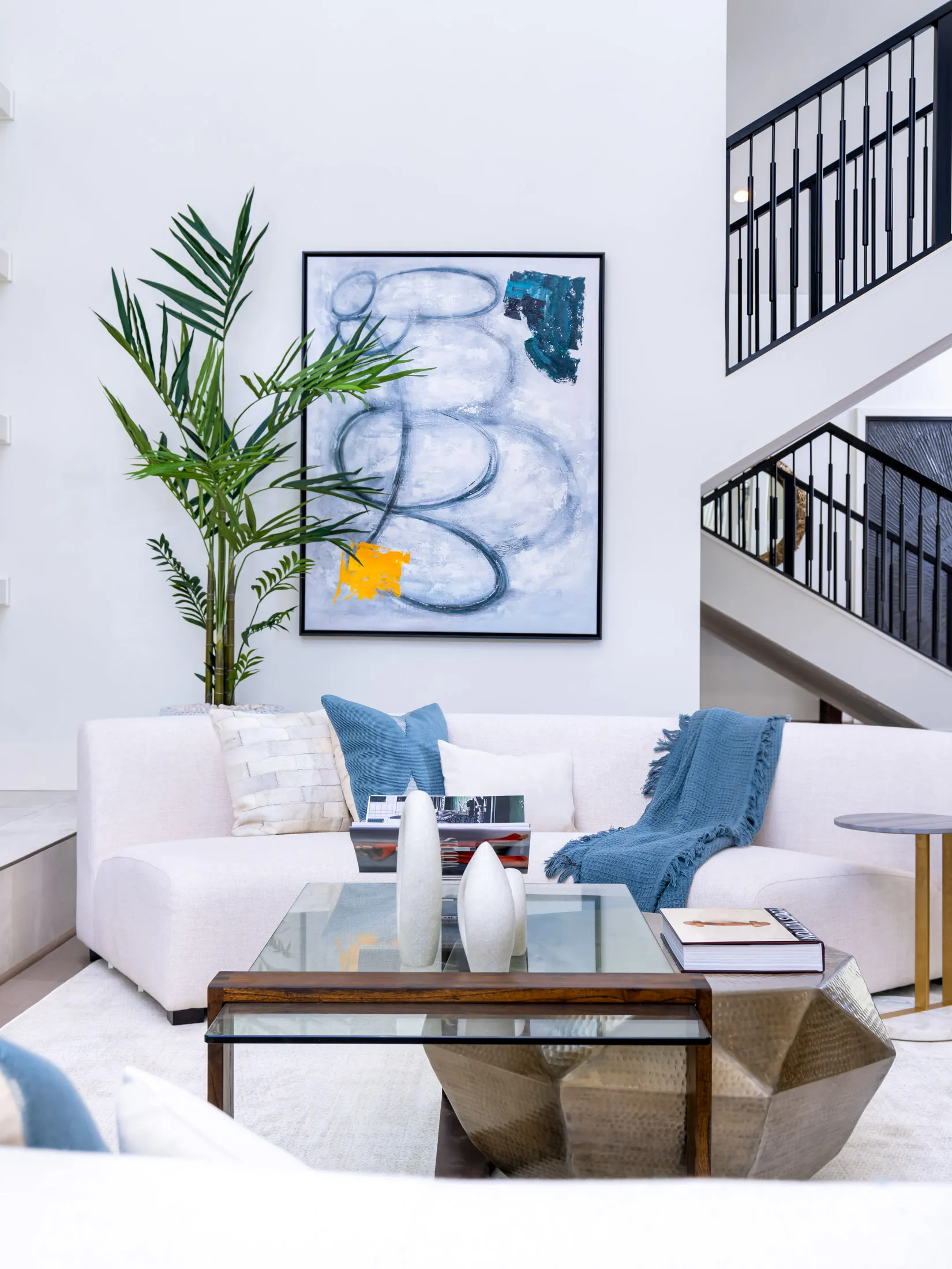 Staged living room with white sectional sofa, glass coffee table and abstract art