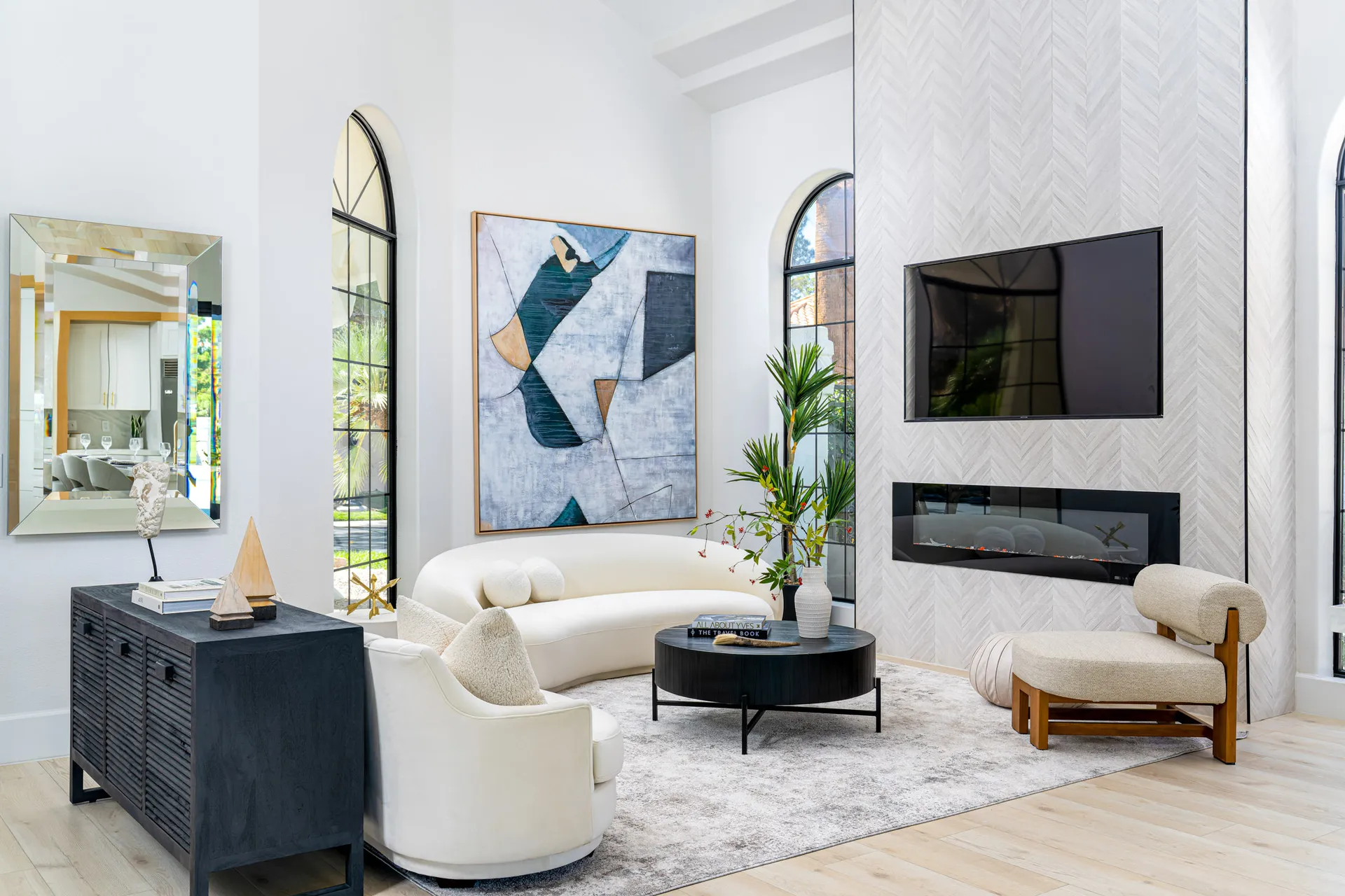 Sunlit staged living room with curved white sofas and layered neutral textures
